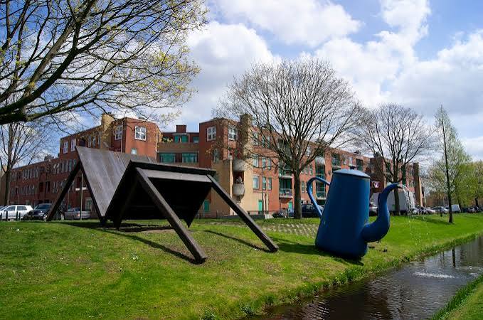 Beeldhouwwerken op een grasveld langs een watergang in Laak